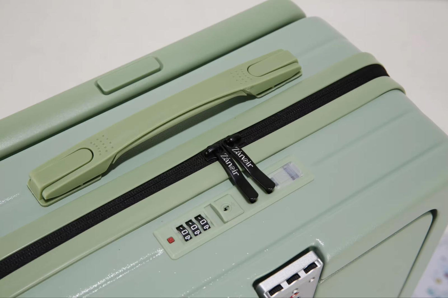 Close-up of forest green suitcase zipper with brand logo