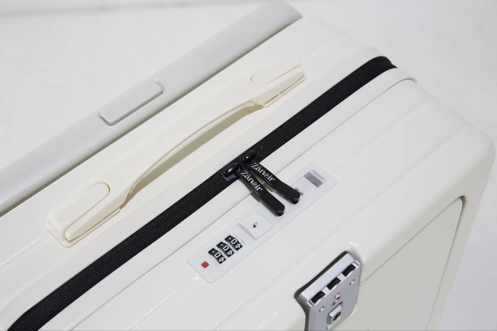 Close-up of polar white suitcase zipper with brand logo
